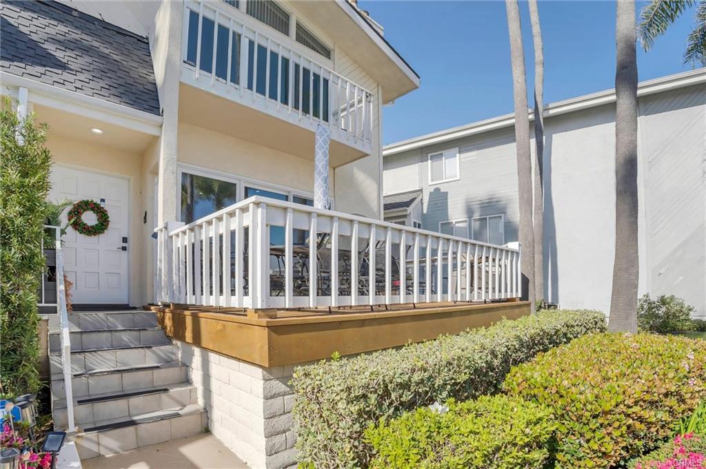 16276 Pacific Cir #B — front elevation of the Bayport townhome with palms and the deck entry