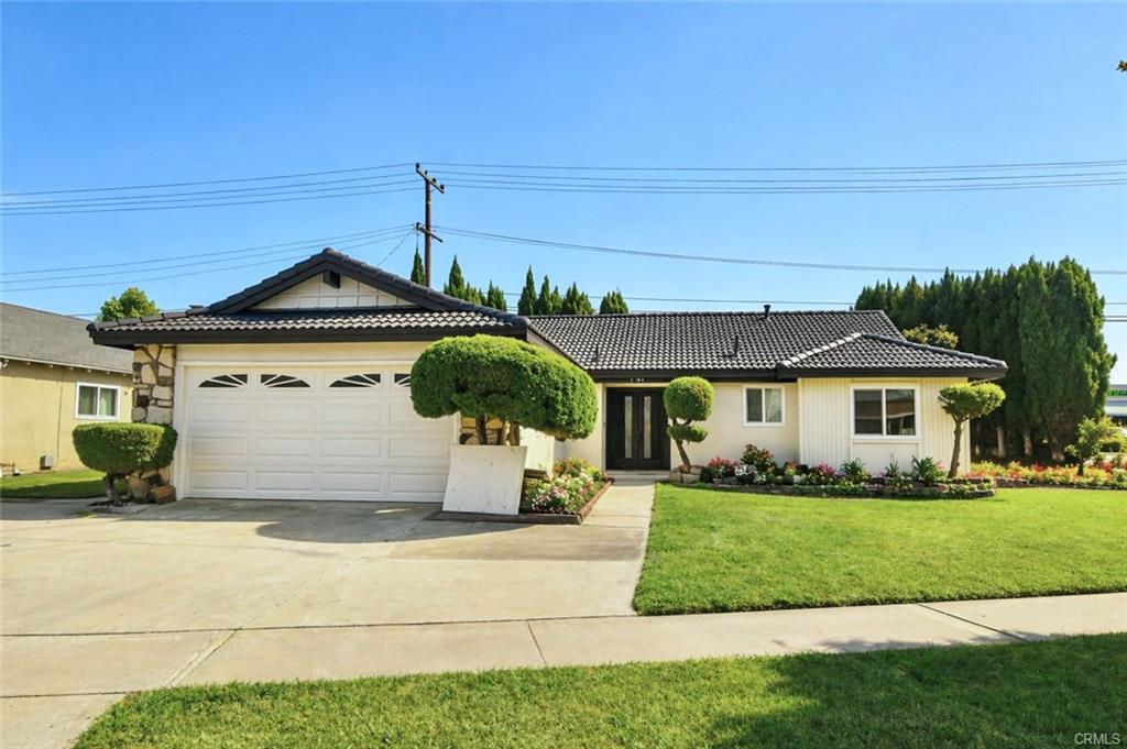 9142 Parliament Ave — front elevation with grey tile roof, wide driveway, and manicured lawn