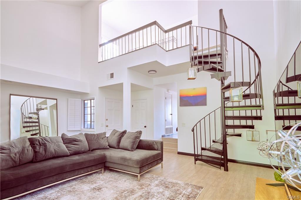 8132 Atwater Cir #202 — living room with soaring vaulted ceilings and spiral staircase to the loft