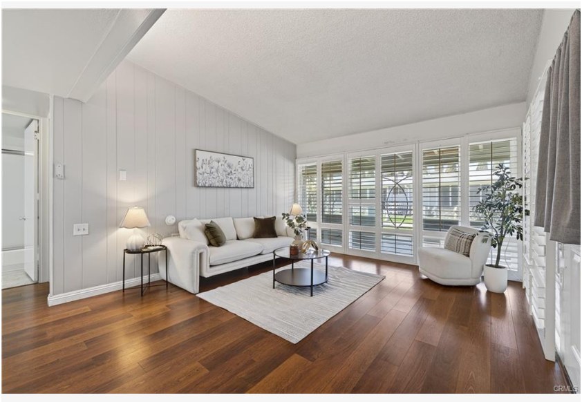 1200 Canoe Brook Dr #19D — living room with vaulted ceilings, plantation shutters, and hardwood-look flooring